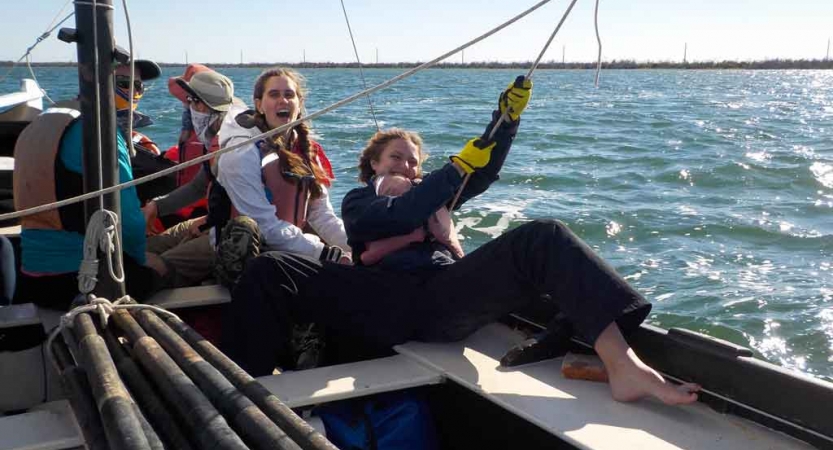 a person holds a rope on a sailboat during an outward bound expedition in florida